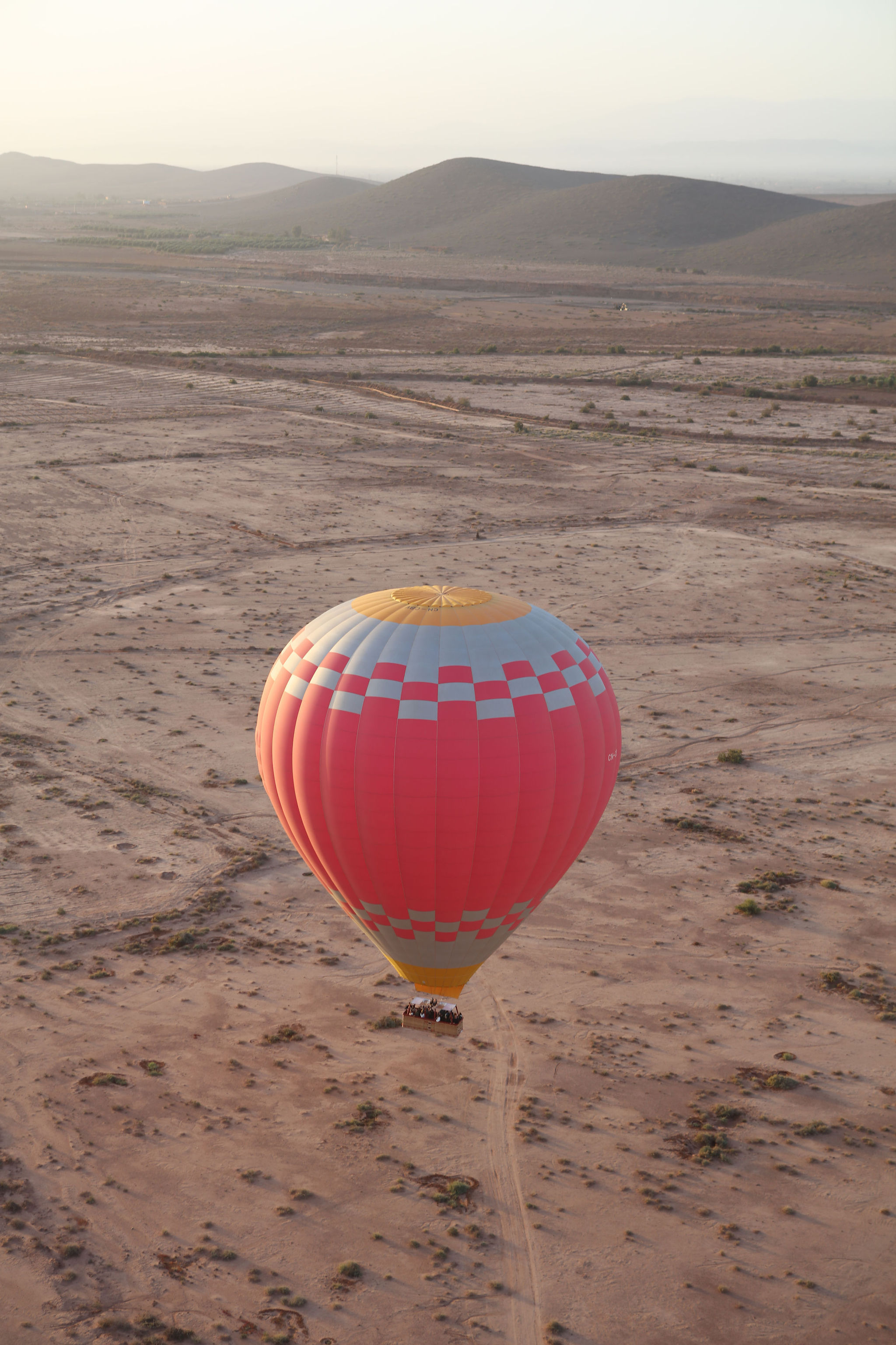 A pink checkered balloon in flight over the desert outside Marrakech, basket packed