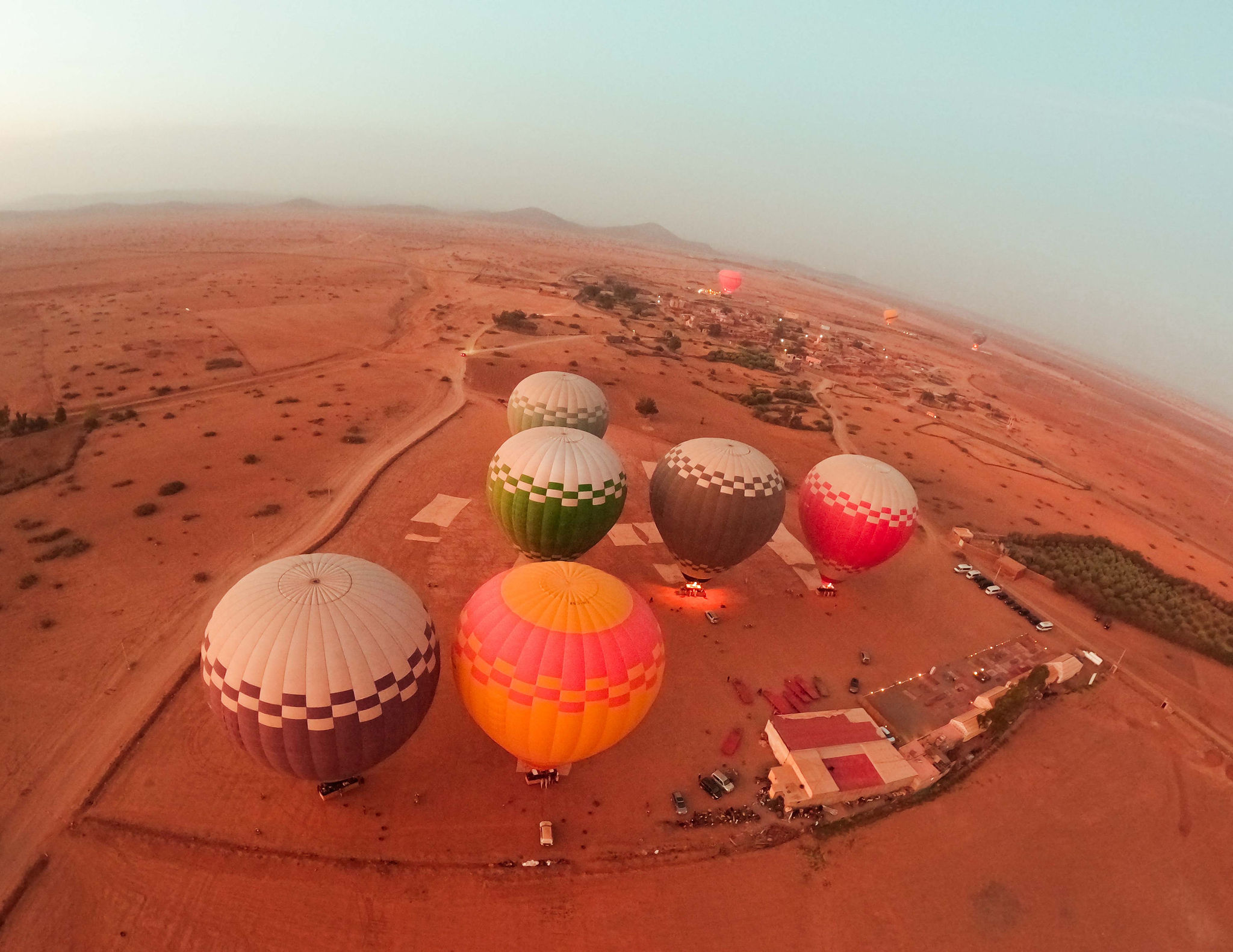 Balloons inflating on the launch field at sunrise, burners lit