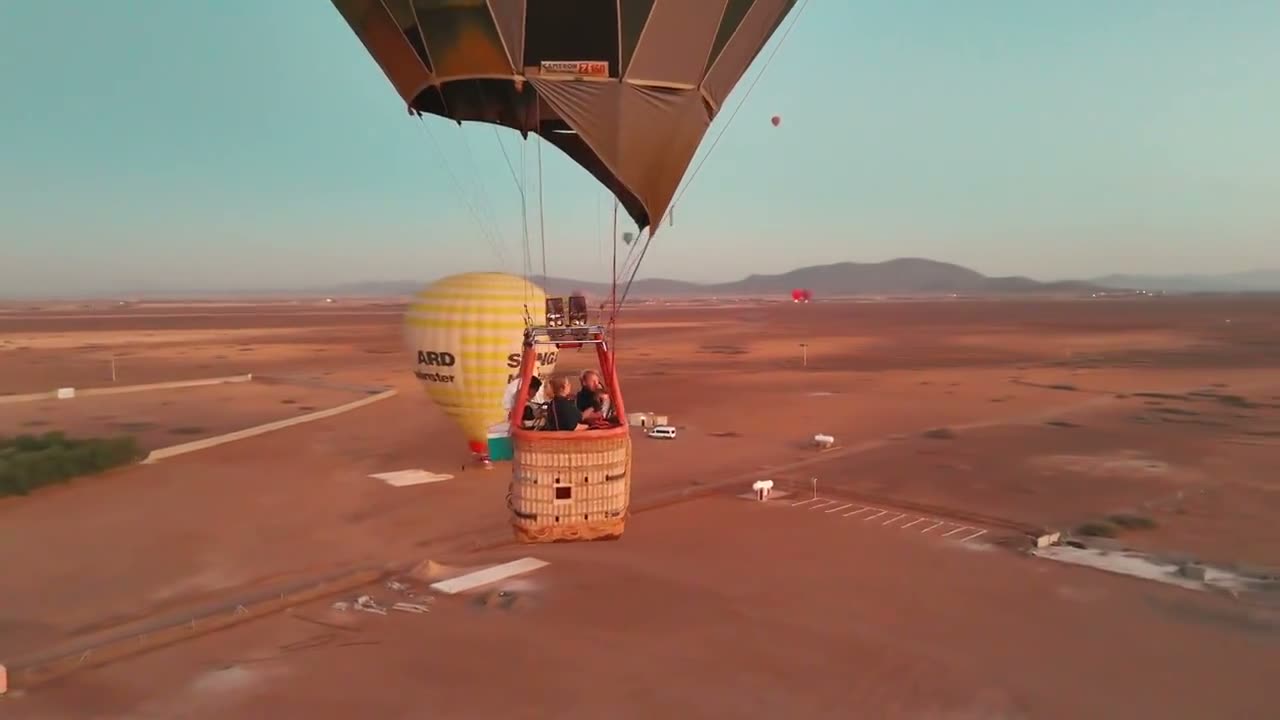 Aerial film of a balloon basket in flight over the Marrakech plain at sunrise