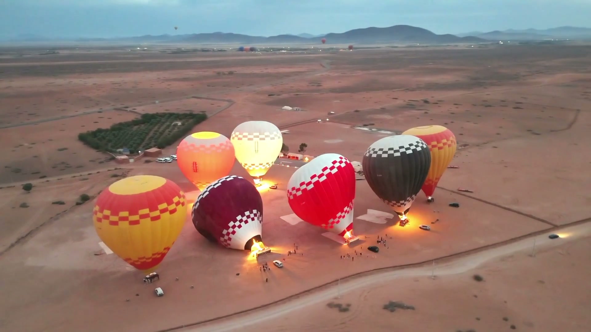 Drone film of envelopes inflating on the launch field outside Marrakech, burners lit