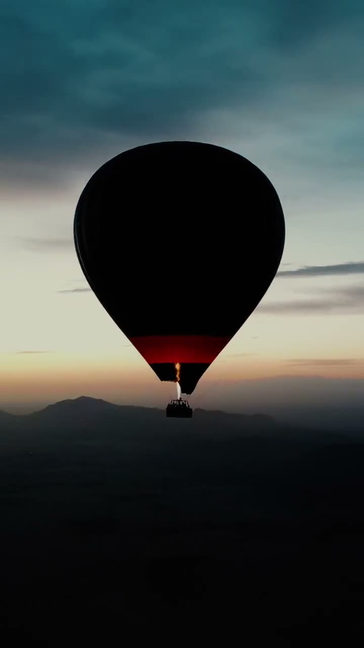 A balloon in silhouette over the Atlas at first light, burner lit