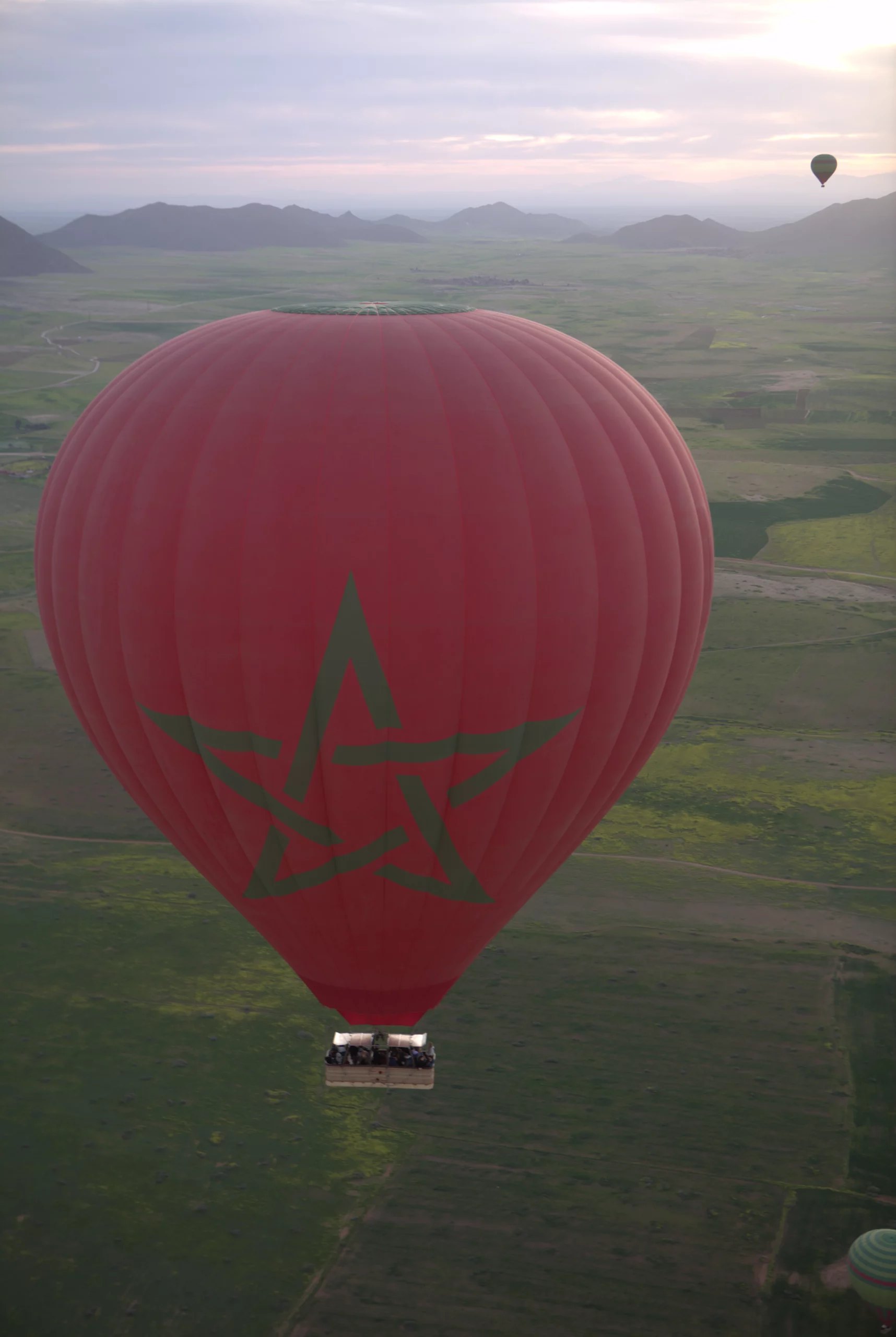 Red balloon with the Moroccan star over countryside at dawn
