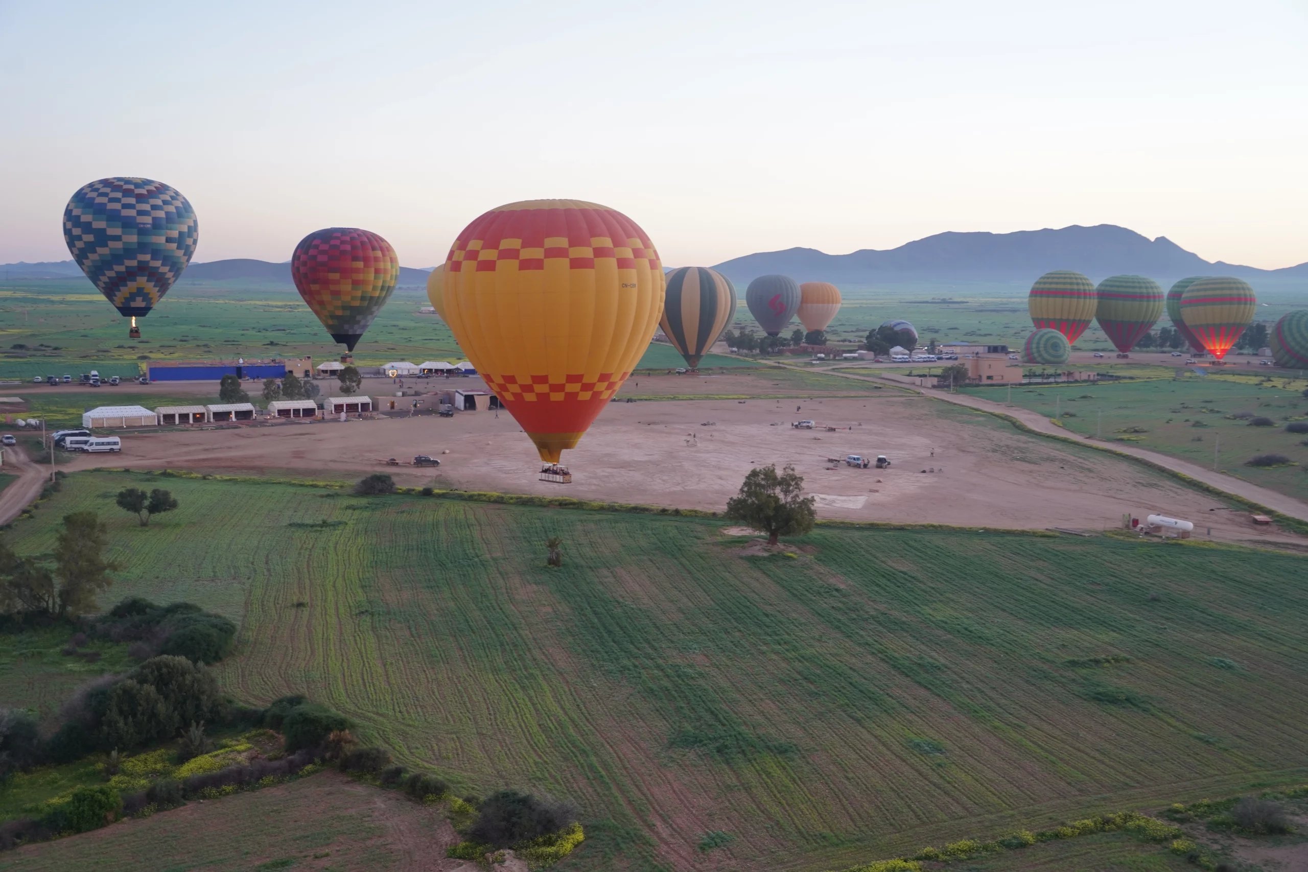 Several balloons launching at dawn from a field outside Marrakech