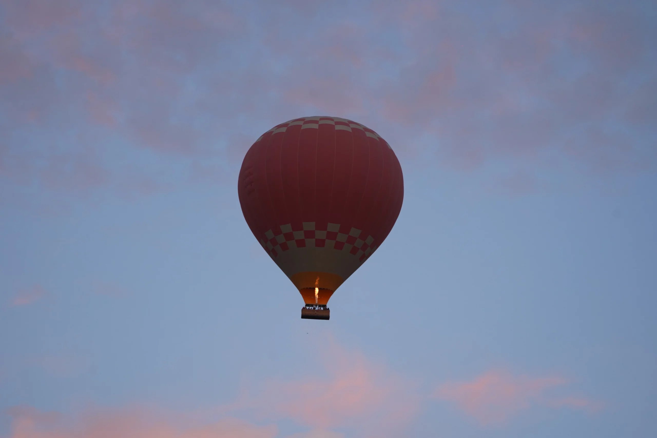 Red balloon in flight at dusk, burner lit